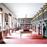 Fotografia de Candida Höfer intitulada Biblioteca América, Universidade de Santiago de Compostela I (2010), retratando um espaço histórico com estantes ornamentadas, bustos e iluminação natural.