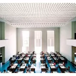 Fotografia de Candida Höfer intitulada Biblioteca Geral da Universidade de Coimbra II (2006), retratando um espaço iluminado com mesas de estudo organizadas simetricamente e um teto geométrico.