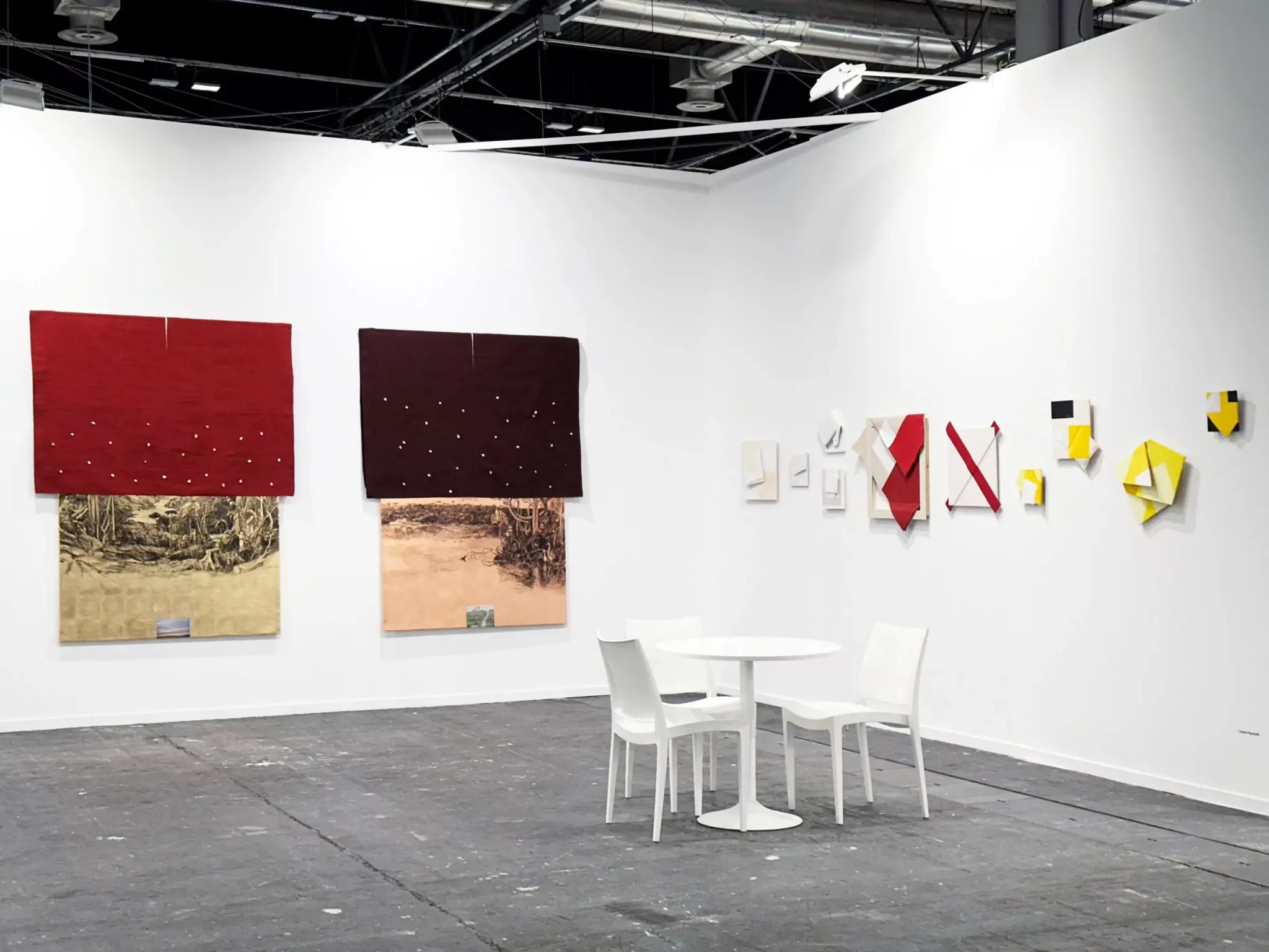 Galeria Leme exibe obras contemporâneas na ARCOmadrid 2025. Paredes brancas com arte geométrica e têxtil, mesa e cadeiras brancas.